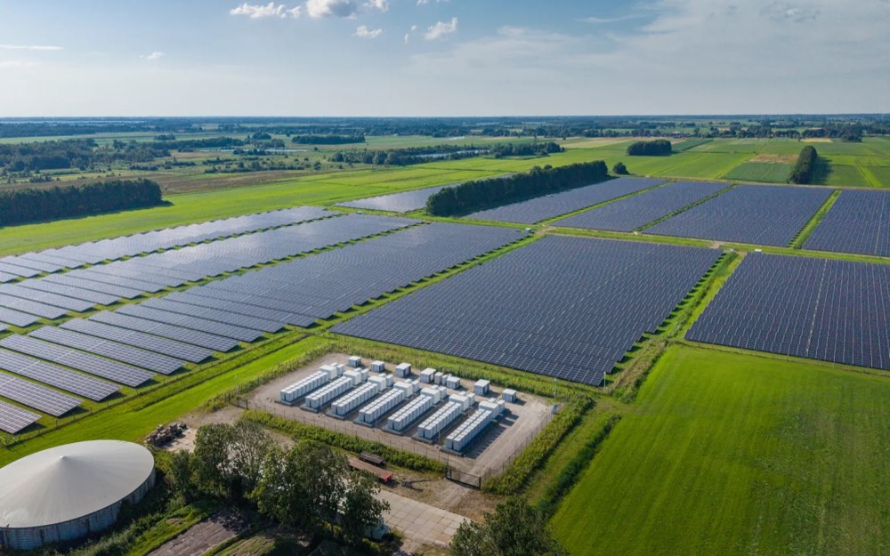 Luftaufnahme eines Solarparks mit Batteriespeicher-Containern zwischen Feldern